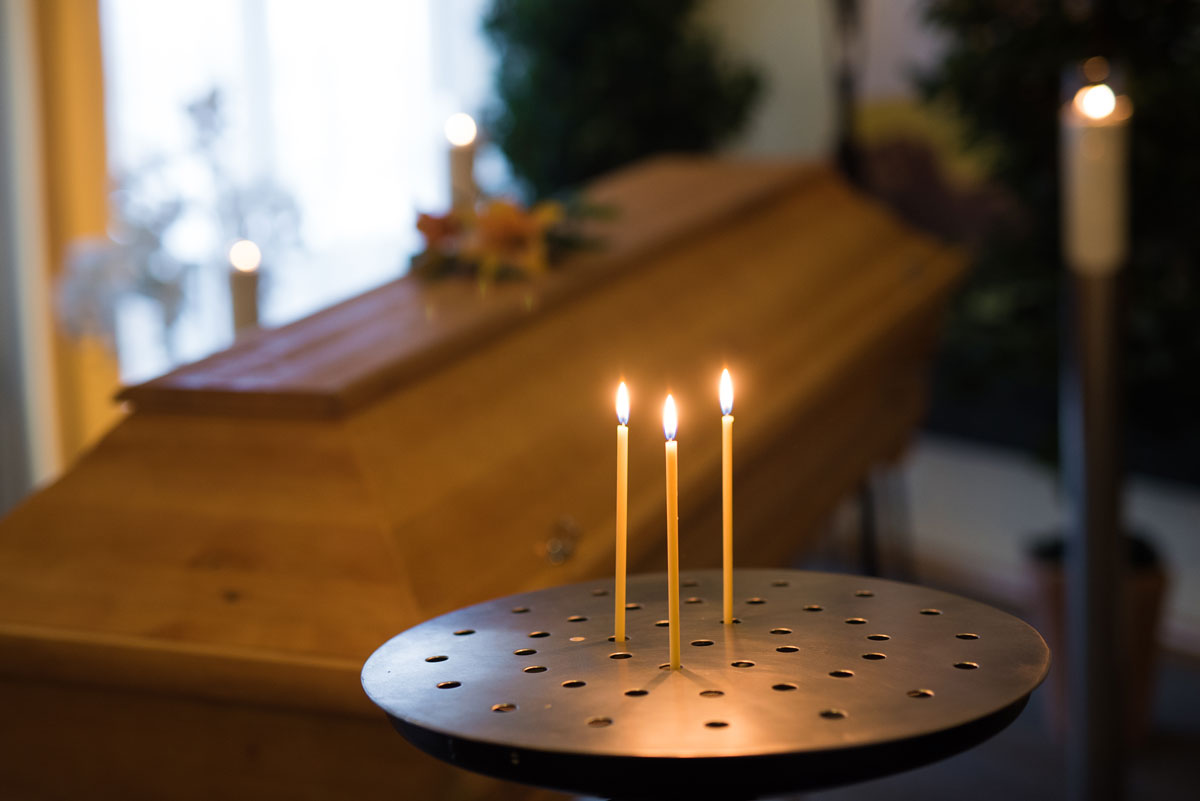 Sargaufbahrung im Bestattungsinstitut Stumpf mit Gedenkkerzen auf einem Kerzenständer